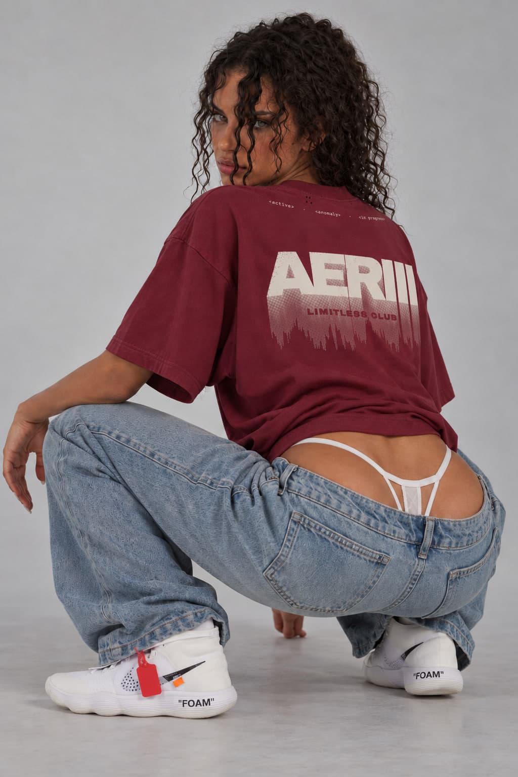 DISSOLVE tee in burgundy, crouching, the back print over the shoulder, on a female model